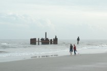A couple strolls past the pilings where there had been a tugboat and barge earlier in the week